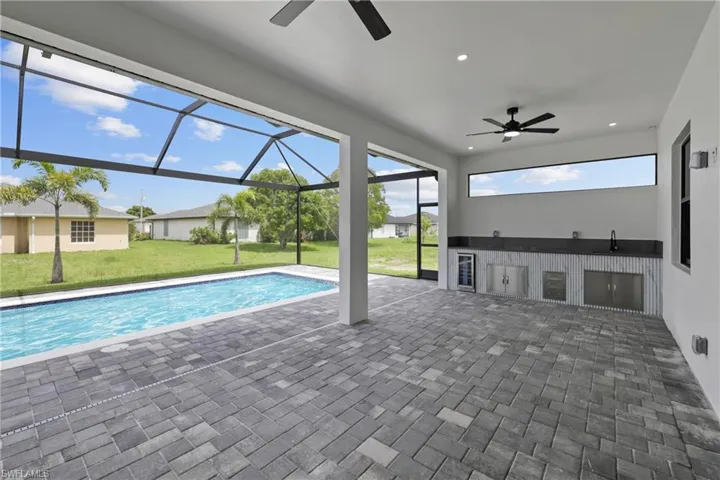 Swimming pool with a ceiling fan, a yard, a patio, and exterior kitchen