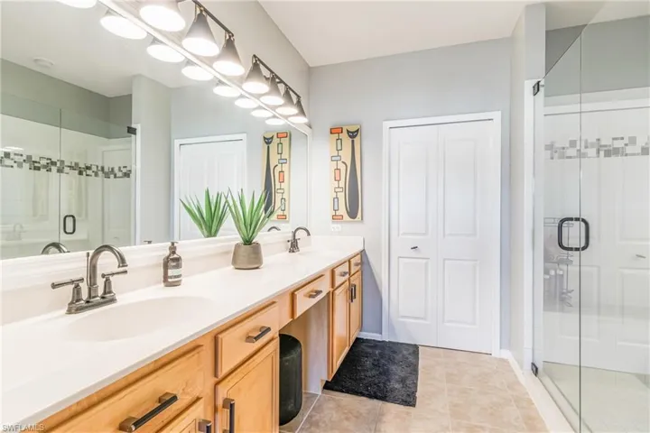 Full bathroom with a large tiled shower, double vanity, and light tile patterned flooring