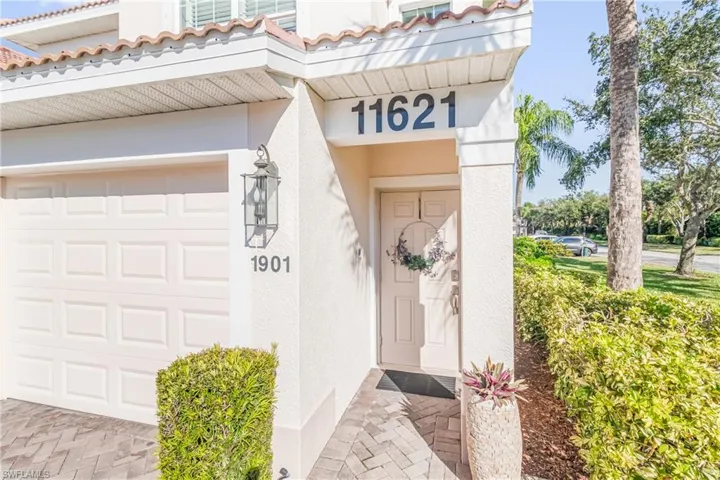 Property entrance with a garage, stucco siding, and a tile roof