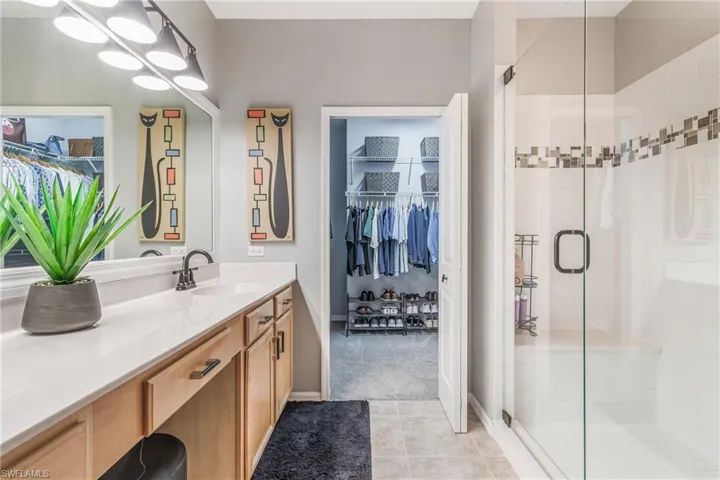 Full bath with a walk in closet, vanity, light tile patterned floors, and a tiled walk-in shower