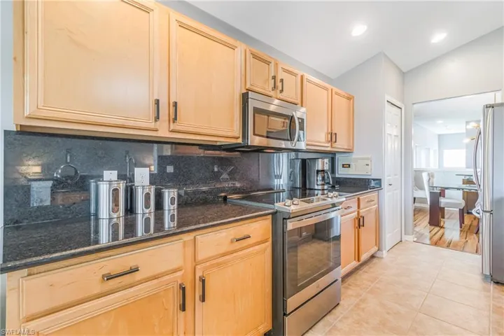 Kitchen featuring stainless appliances with granite countertops and backsplash, light cabinets, and recessed lighting