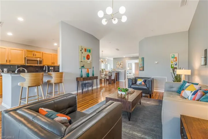 Living area with a chandelier, laminate wood-style floors, and recessed lighting