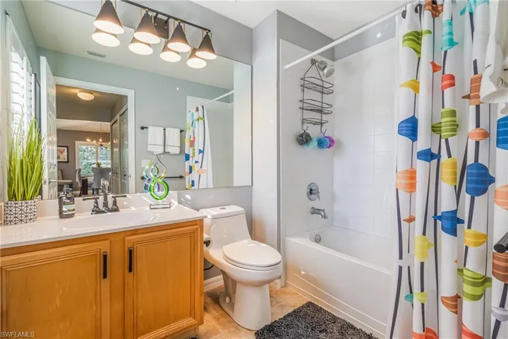Full bathroom featuring a tiled shower / tub combo with curtain, vanity, and light tile patterned floors