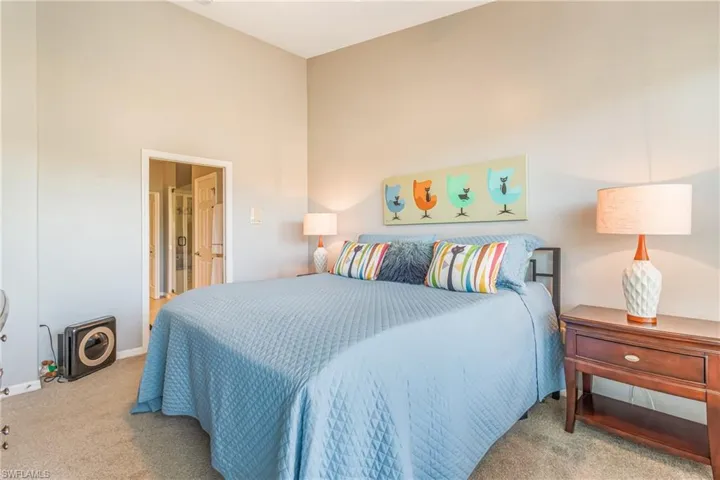 Carpeted bedroom with a vaulted ceiling and baseboards