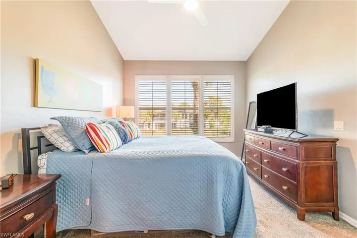 Bedroom featuring light carpet, vaulted ceiling, and a ceiling fan