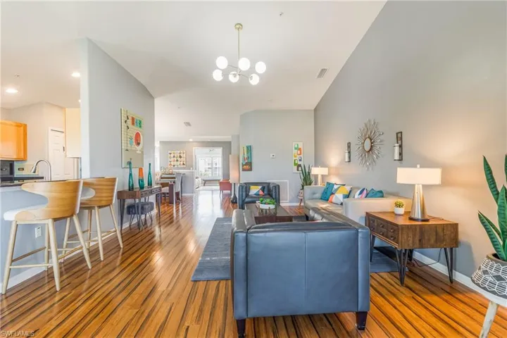 Living room with light wood-style flooring, vaulted ceiling, and a chandelier