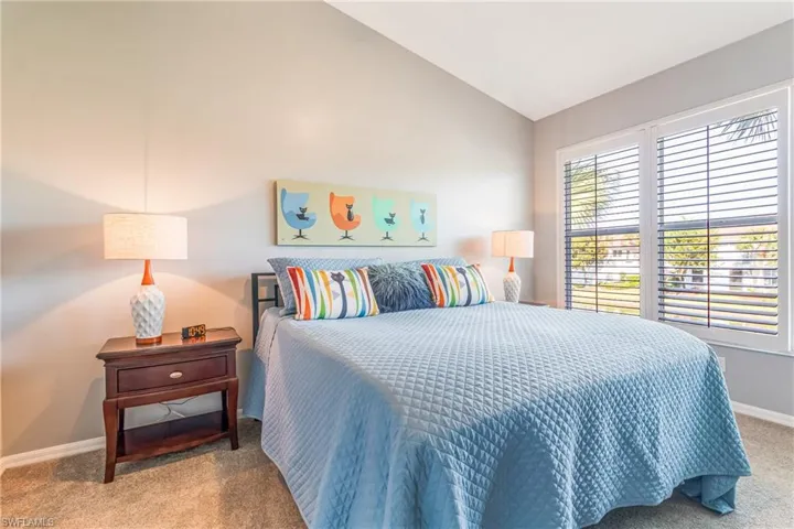Bedroom with vaulted ceiling and light colored carpet
