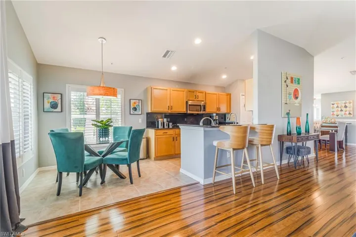 Kitchen with granite backsplash and countertops, a breakfast bar area, light tile patterned floors
