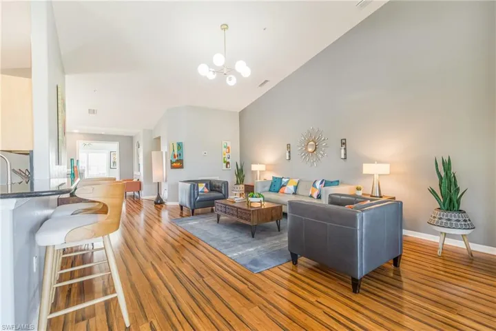 Living room with a chandelier, laminate wood-style floors, and high vaulted ceiling