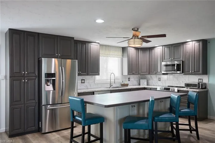 Kitchen featuring a breakfast bar area, light wood-type flooring, a sink, and stainless steel appliances