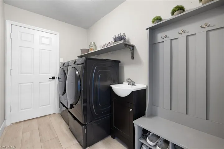 Laundry room with washer and dryer, laundry area, a sink, and light wood-style flooring
