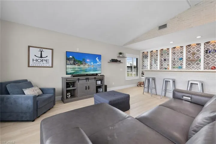 Living area featuring lofted ceiling, visible vents, baseboards, and wood finished floors
