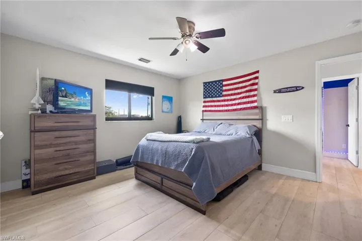 Bedroom featuring a ceiling fan, baseboards, visible vents, and wood finished floors