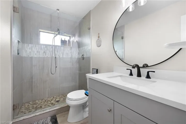 Full bath with toilet, a shower stall, wood finished floors, and vanity