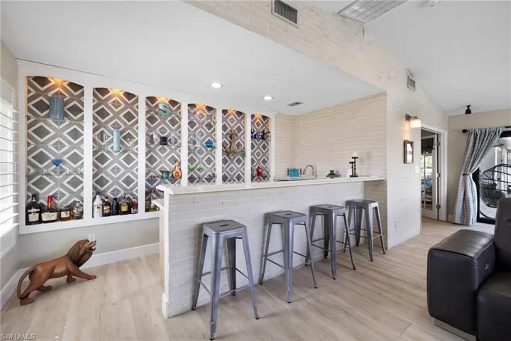 Kitchen with visible vents, brick wall, wood finished floors, vaulted ceiling, and a kitchen bar