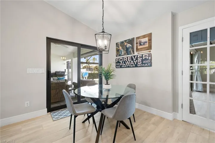 Dining area featuring light wood-style floors, baseboards, vaulted ceiling, and a chandelier