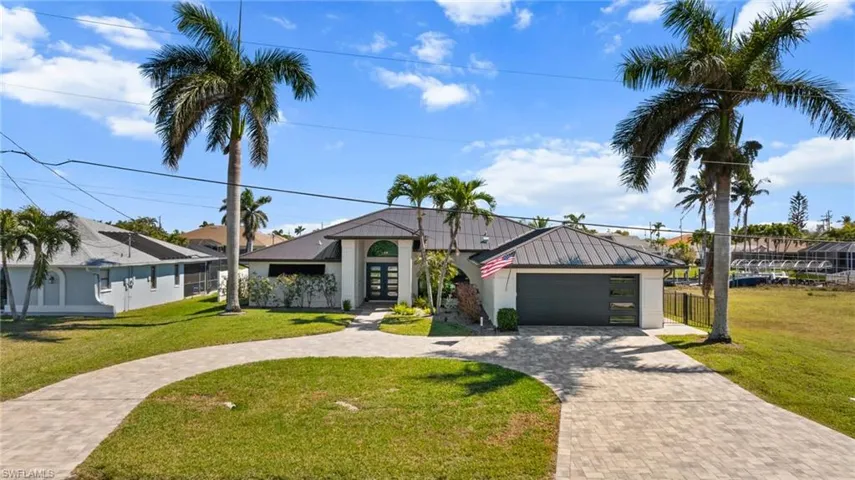 View of front facade featuring decorative driveway, stucco siding, a front yard, a standing seam roof, and metal roof