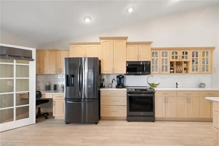 Kitchen featuring lofted ceiling, light brown cabinetry, appliances with stainless steel finishes, and light countertops