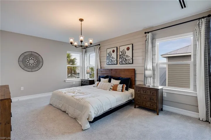 Master Carpeted bedroom featuring multiple windows and a chandelier