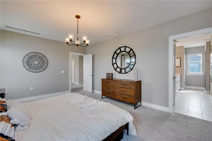 Master Bedroom with light colored carpet, a chandelier, and connected bathroom