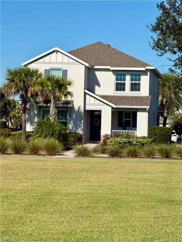 front of house, shingled roof, a front yard, and stucco siding