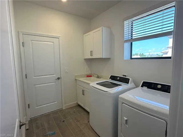 Washroom featuring washer and dryer, dark wood-type flooring, sink, and cabinets