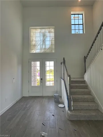 Entrance foyer with a high ceiling, french doors, and wood-type flooring