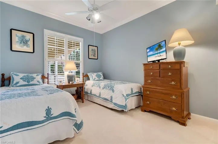 Carpeted bedroom featuring ceiling fan and ornamental molding