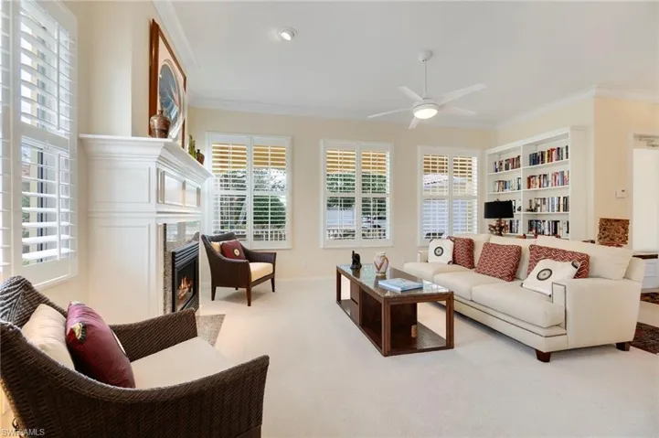 Living room featuring ceiling fan, ornamental molding, light carpet, and a wealth of natural light