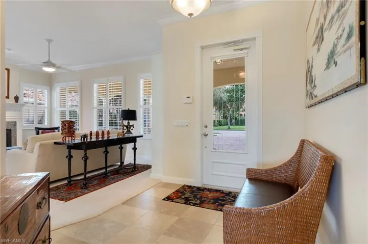 Tiled foyer entrance with ceiling fan and ornamental molding