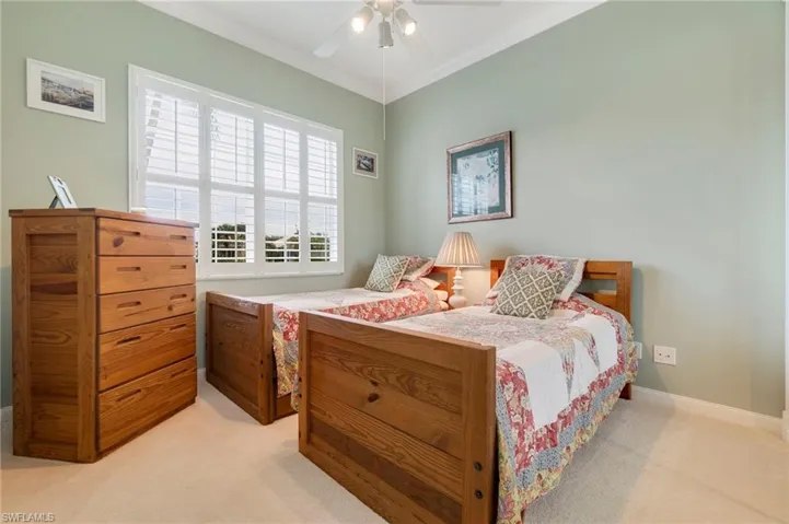 Carpeted bedroom with ceiling fan and ornamental molding