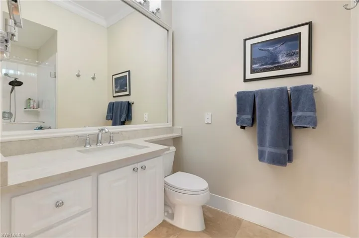Bathroom featuring tile patterned floors, crown molding, an enclosed shower, toilet, and vanity