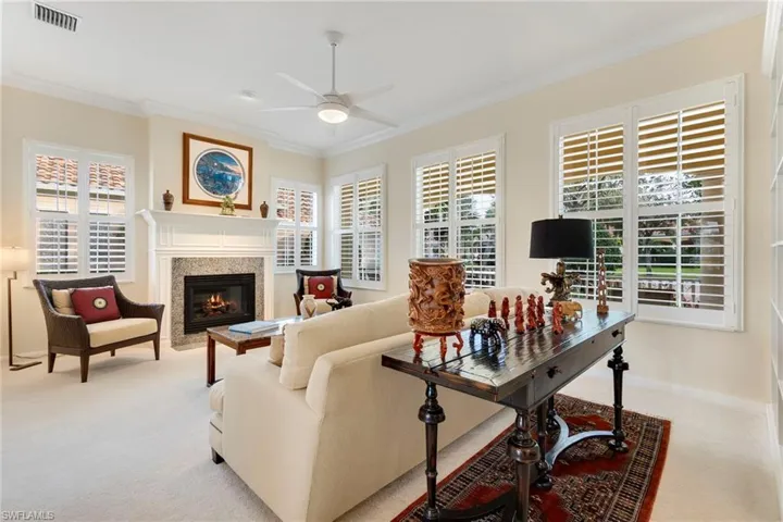 Carpeted living room with ceiling fan, fireplace, and ornamental molding
