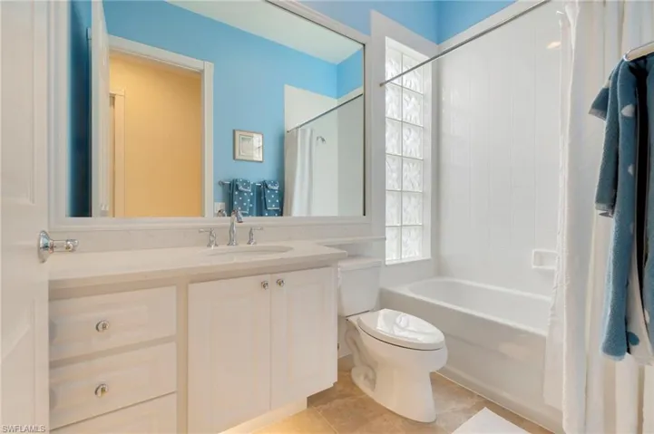Full bathroom featuring tile patterned floors, vanity, toilet, and shower / tub combo with curtain