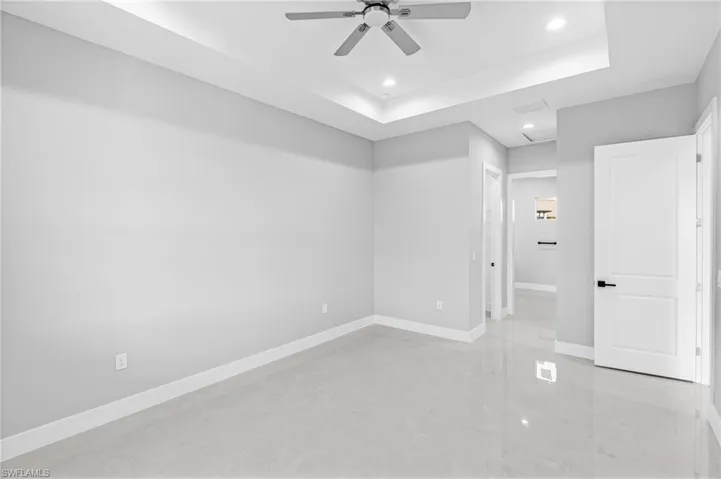 Spare room featuring a raised ceiling, recessed lighting, a ceiling fan, concrete floors, and attic access