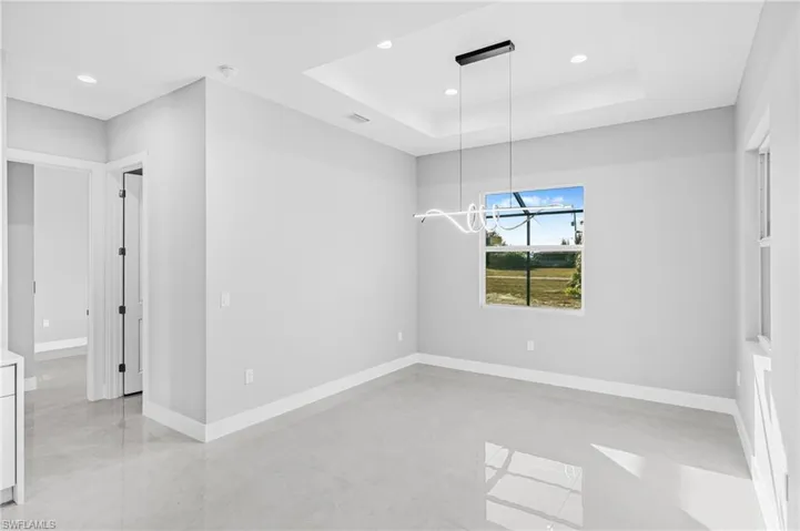 Unfurnished dining area with recessed lighting and a raised ceiling