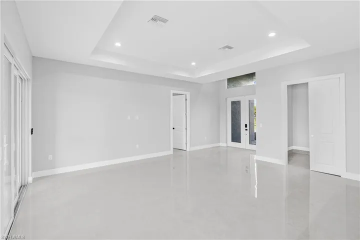 Unfurnished bedroom featuring access to exterior, french doors, concrete floors, recessed lighting, and a raised ceiling