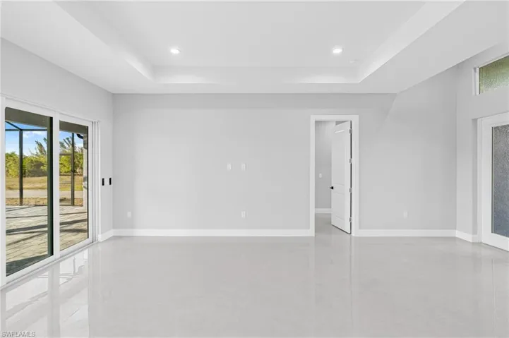 Empty room with finished concrete flooring, a tray ceiling, and recessed lighting