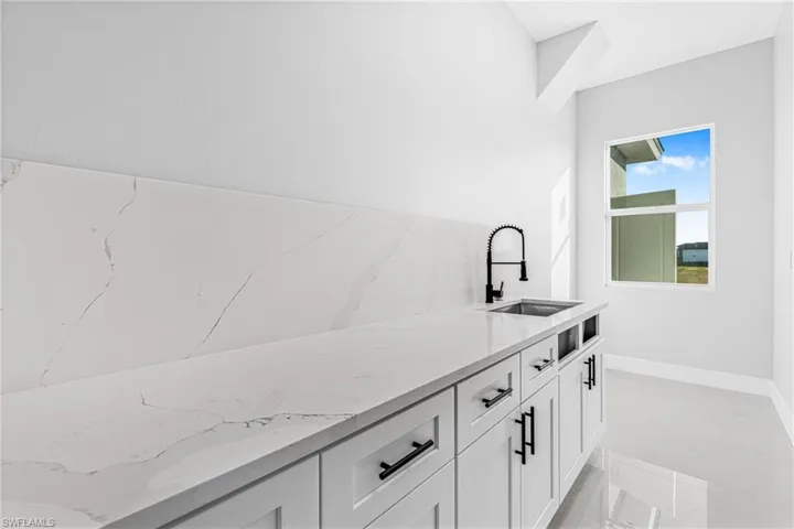 Bar featuring light stone countertops and white cabinetry