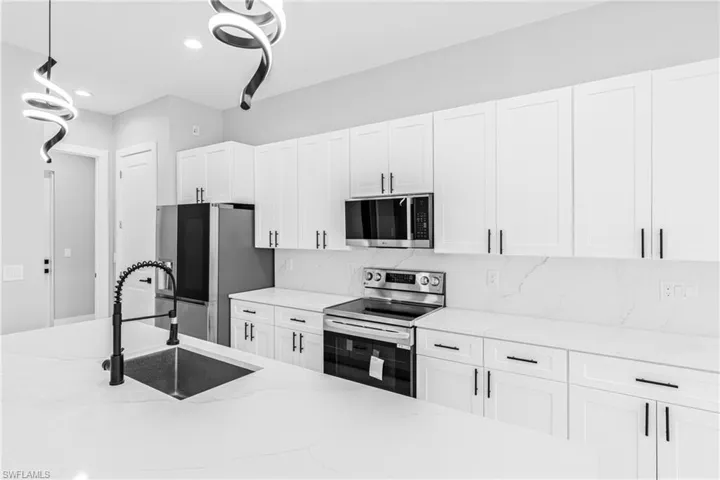 Kitchen featuring appliances with stainless steel finishes, white cabinetry, light stone countertops, recessed lighting, and decorative backsplash