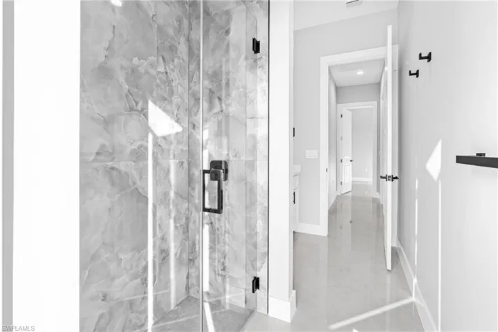 Full bath with a marble finish shower and baseboards