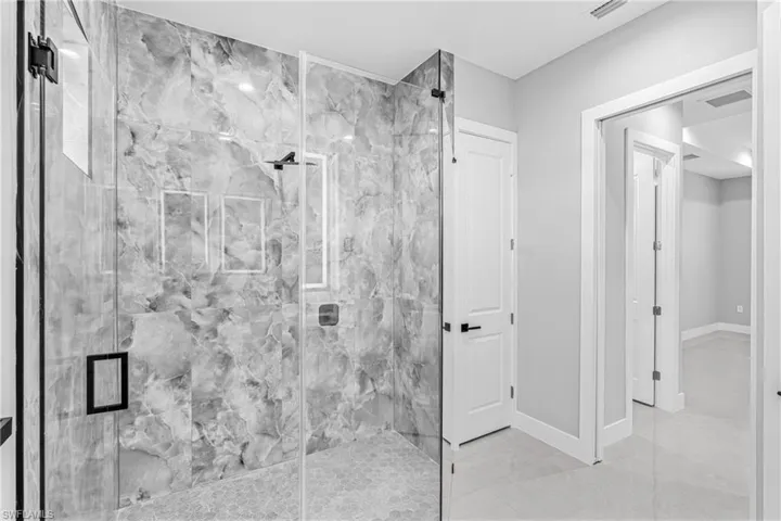 Bathroom with a marble finish shower and baseboards