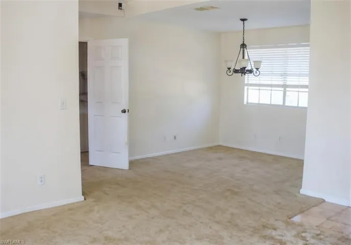 Unfurnished room with light colored carpet and suspended lighting