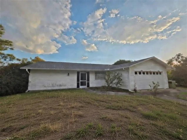 Single story home with a front yard, an attached garage, and driveway