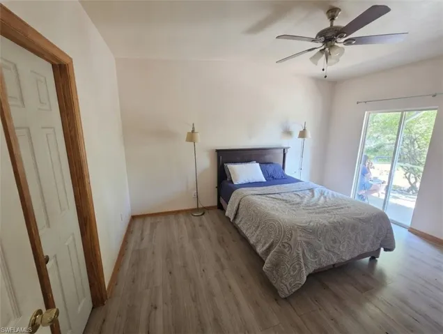 Bedroom featuring wood finished floors, access to exterior, a ceiling fan, and vaulted ceiling
