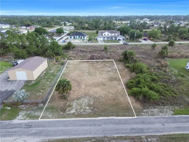 Aerial perspective of suburban area featuring property parcel outlined and a tree filled landscape