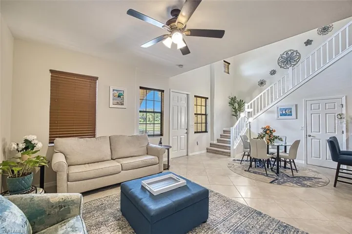 Living room with stairway, a ceiling fan, tile patterned floors, and baseboards