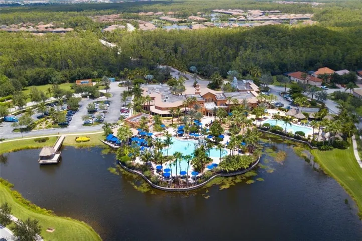 Aerial overview of property's location with a large body of water, a pool, and a heavily wooded area