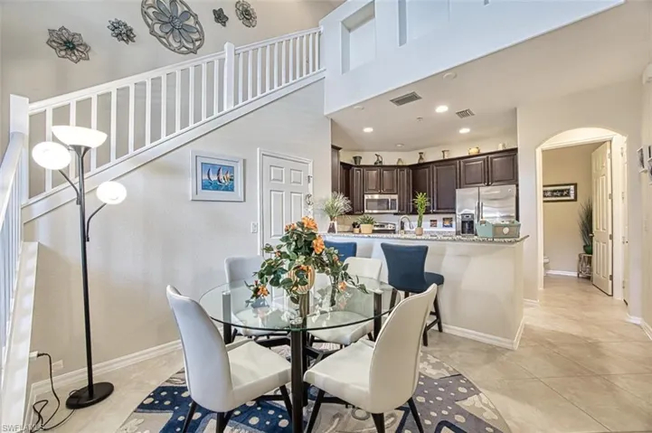 Dining area with arched walkways, light tile patterned floors, recessed lighting, and baseboards