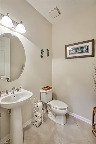 Half bathroom with toilet, tile patterned flooring, and baseboards